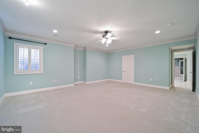 empty room with light carpet, ornamental molding, a ceiling fan, and baseboards