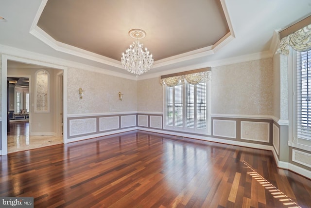 unfurnished room featuring a wainscoted wall, a decorative wall, a raised ceiling, and an inviting chandelier