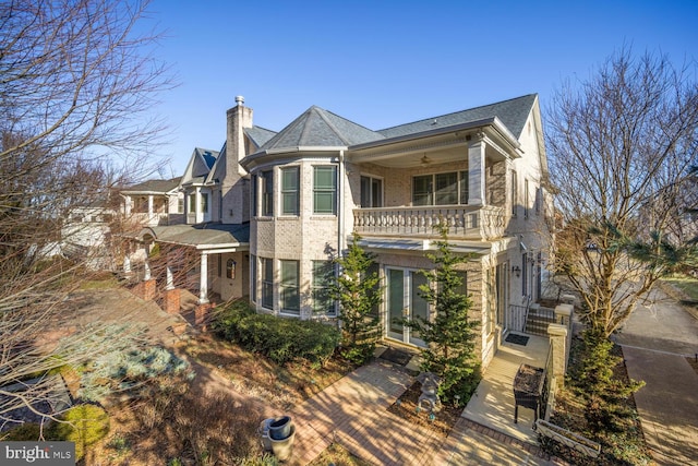 view of front of house with a chimney, brick siding, and a balcony