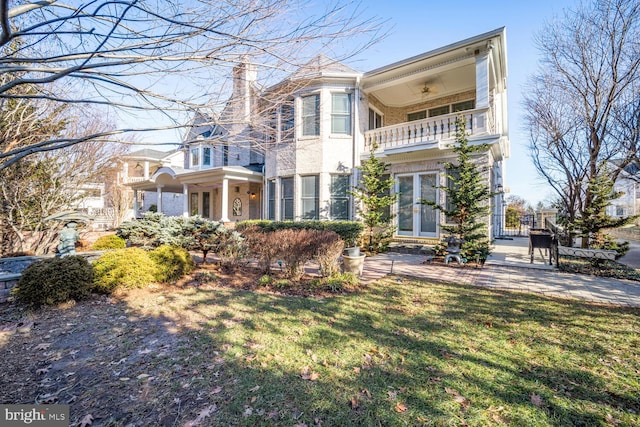 view of front of property with a chimney, a balcony, and a front lawn