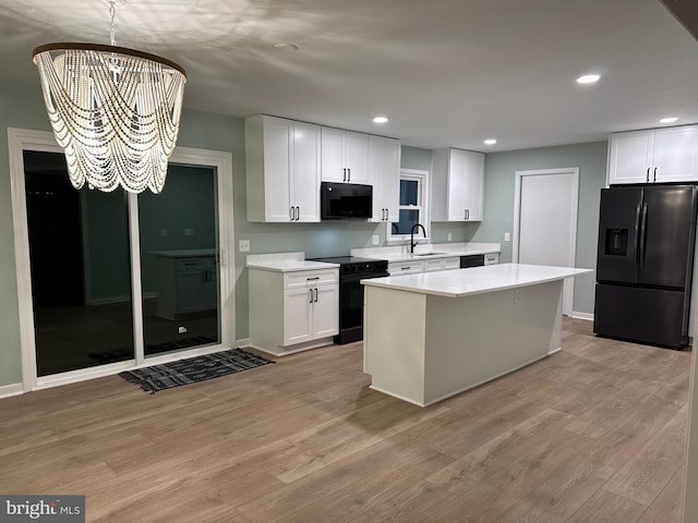 kitchen featuring a kitchen island, white cabinetry, a notable chandelier, and black appliances