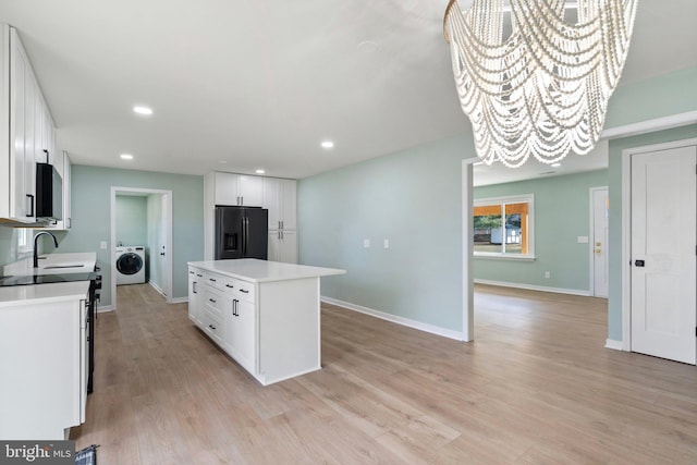 kitchen featuring white cabinets, refrigerator with ice dispenser, a chandelier, washer / dryer, and a center island