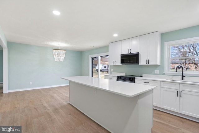 kitchen featuring electric range, white cabinetry, a kitchen island, and sink