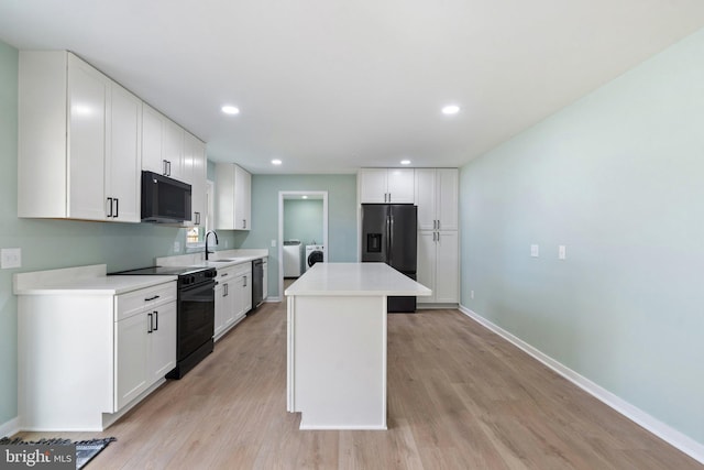 kitchen featuring white cabinetry, light hardwood / wood-style flooring, a kitchen island, and black appliances