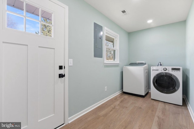 laundry area featuring electric panel, washer and clothes dryer, plenty of natural light, and light hardwood / wood-style flooring