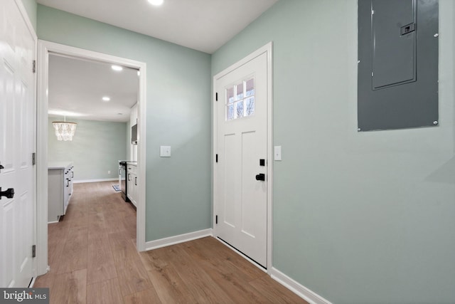 foyer entrance featuring a notable chandelier, light wood-type flooring, and electric panel