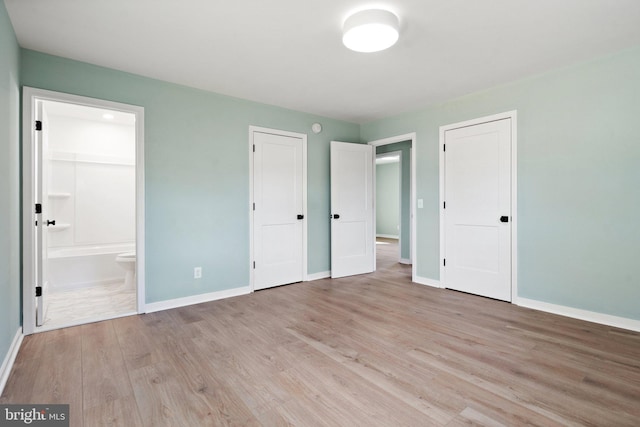 unfurnished bedroom with ensuite bathroom and light hardwood / wood-style flooring