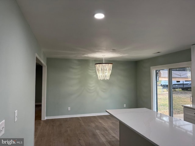 unfurnished dining area featuring dark hardwood / wood-style flooring and a chandelier