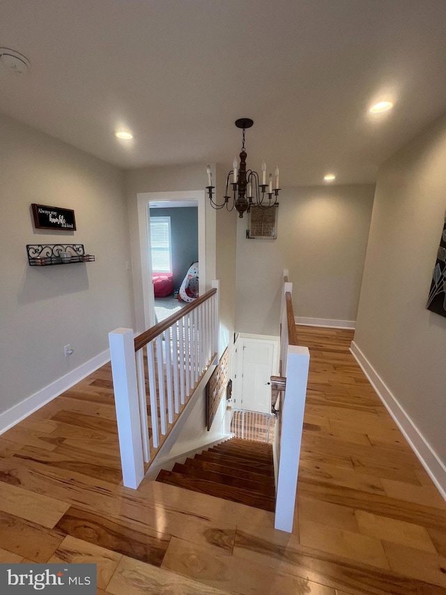 stairs featuring a chandelier and wood-type flooring