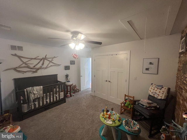 bedroom featuring carpet flooring, ceiling fan, a crib, and a closet