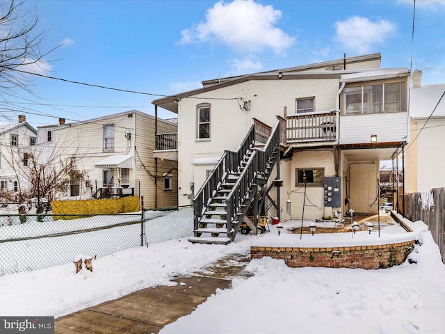 snow covered rear of property featuring a sunroom and a deck