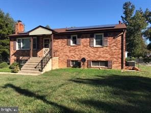 view of front of house featuring a chimney, a front yard, and roof mounted solar panels