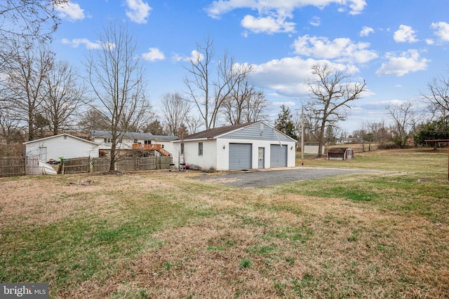 view of yard with a detached garage, an outdoor structure, and fence