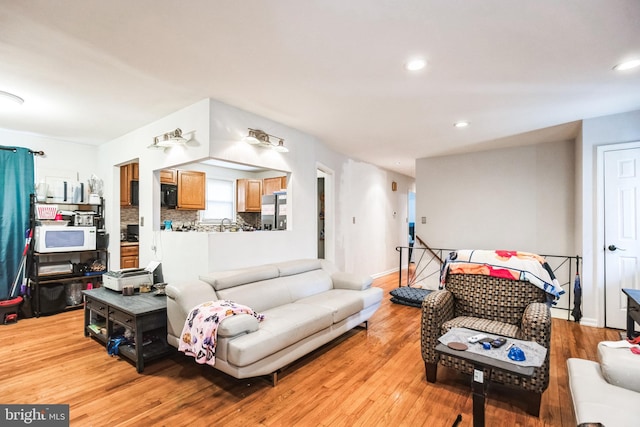 living area featuring baseboards, light wood finished floors, and recessed lighting