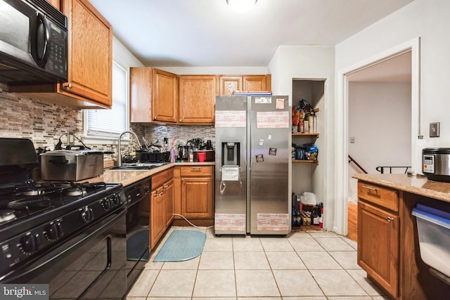 kitchen featuring light tile patterned flooring, a sink, black appliances, tasteful backsplash, and brown cabinetry