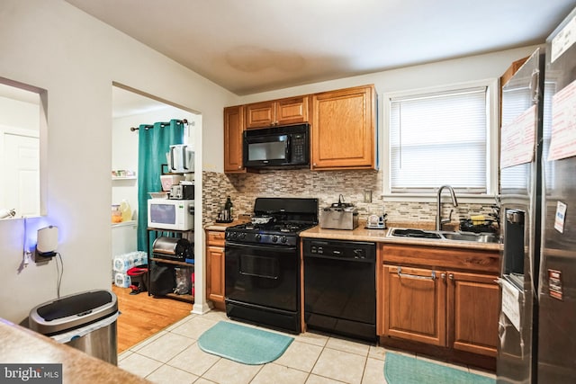 kitchen with light countertops, a sink, backsplash, and black appliances