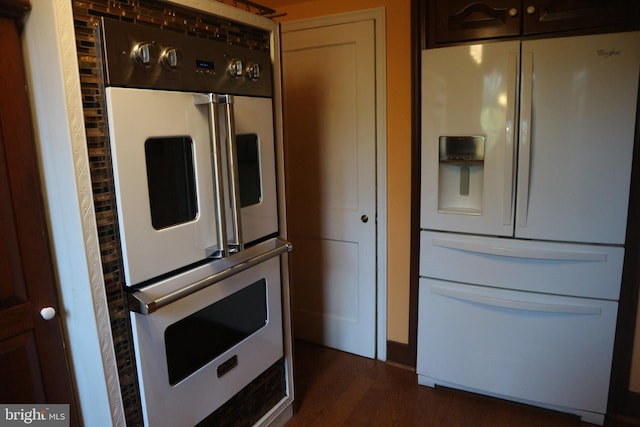 kitchen featuring dark brown cabinets, dark hardwood / wood-style floors, and white appliances