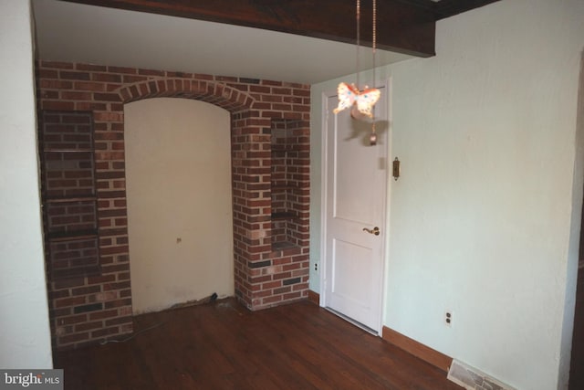 empty room featuring brick wall and dark hardwood / wood-style floors