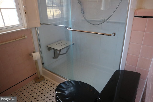 bathroom with tile patterned flooring, a shower with shower door, and tile walls