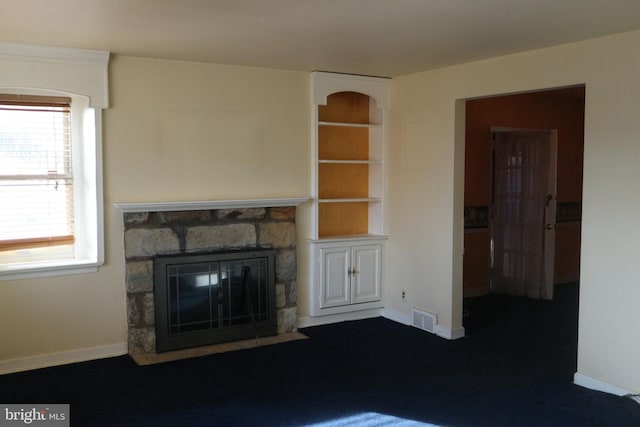 unfurnished living room with a healthy amount of sunlight, built in features, and a fireplace