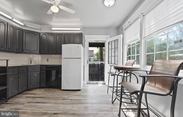 kitchen with decorative backsplash, ceiling fan, sink, black dishwasher, and white fridge