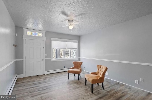 sitting room featuring hardwood / wood-style floors, a textured ceiling, and baseboard heating