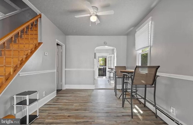 dining room featuring ceiling fan, dark wood-type flooring, and a baseboard heating unit