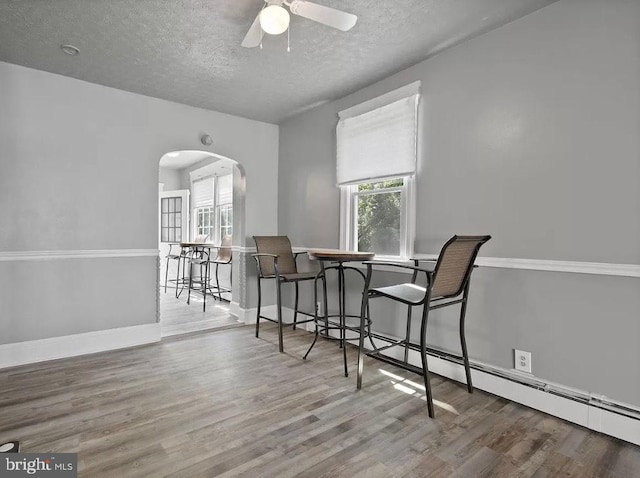 dining space with ceiling fan, wood-type flooring, and a textured ceiling