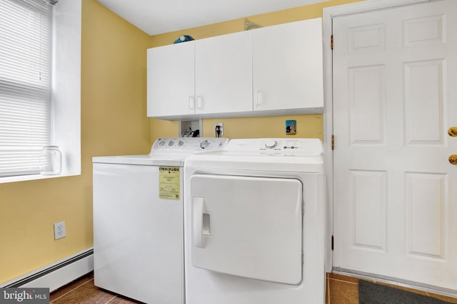 clothes washing area with washer and clothes dryer, cabinets, baseboard heating, and dark tile patterned flooring