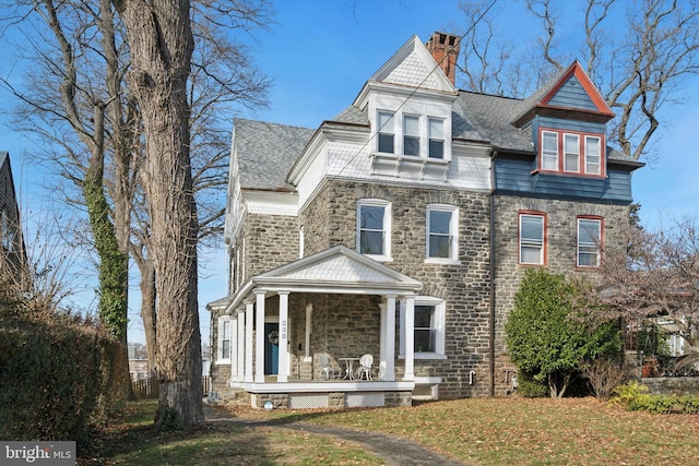 victorian-style house featuring a porch and a front yard