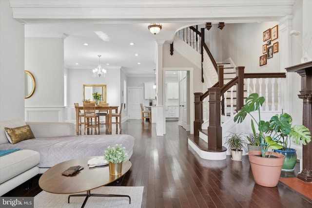 living room with crown molding, dark wood-type flooring, and an inviting chandelier