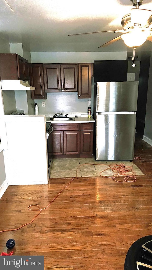 kitchen featuring dark brown cabinets, stainless steel fridge, light wood-type flooring, and sink