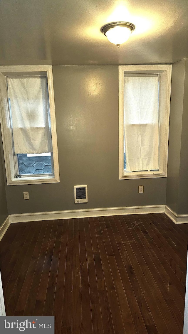 empty room with dark wood-type flooring and heating unit