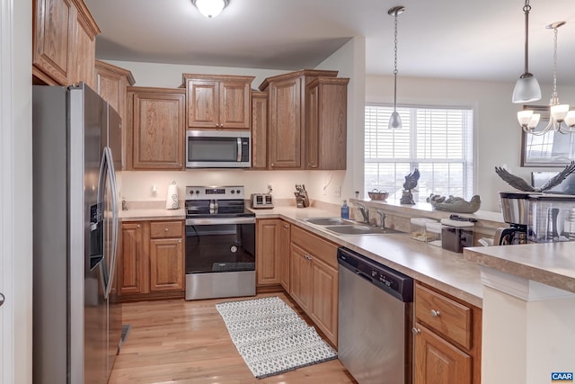 kitchen featuring sink, hanging light fixtures, light hardwood / wood-style flooring, a notable chandelier, and stainless steel appliances