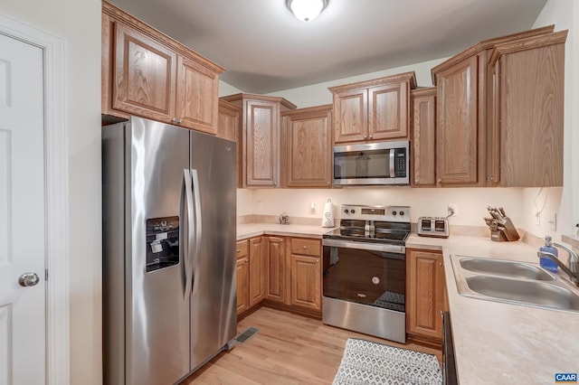 kitchen with light wood-type flooring, stainless steel appliances, and sink