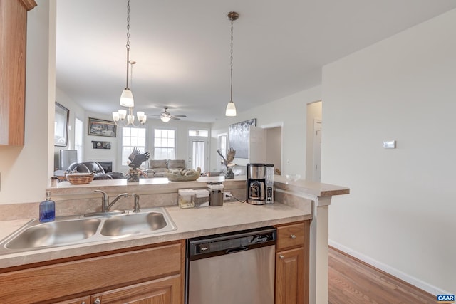 kitchen with sink, light hardwood / wood-style flooring, stainless steel dishwasher, pendant lighting, and ceiling fan with notable chandelier