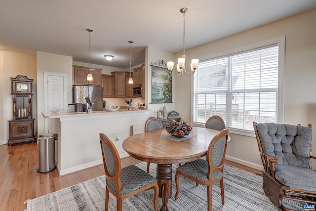 dining space featuring light wood-type flooring and a notable chandelier