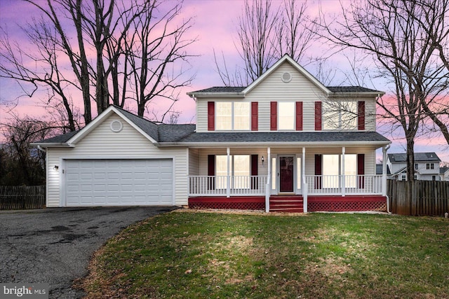 view of front facade with covered porch, a garage, and a lawn