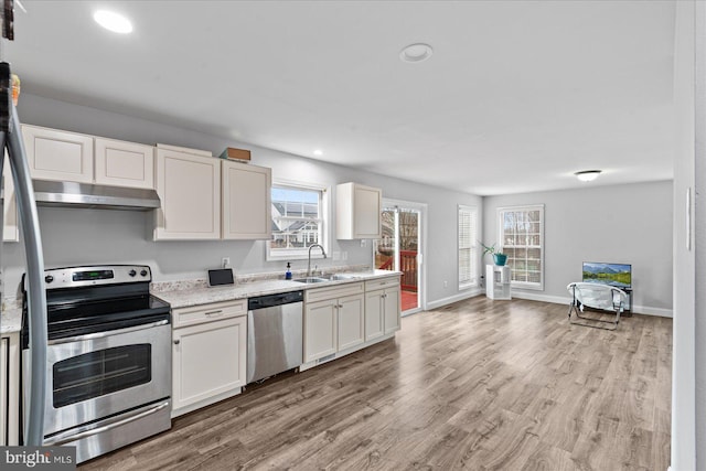 kitchen with stainless steel appliances, light stone counters, a wealth of natural light, and sink