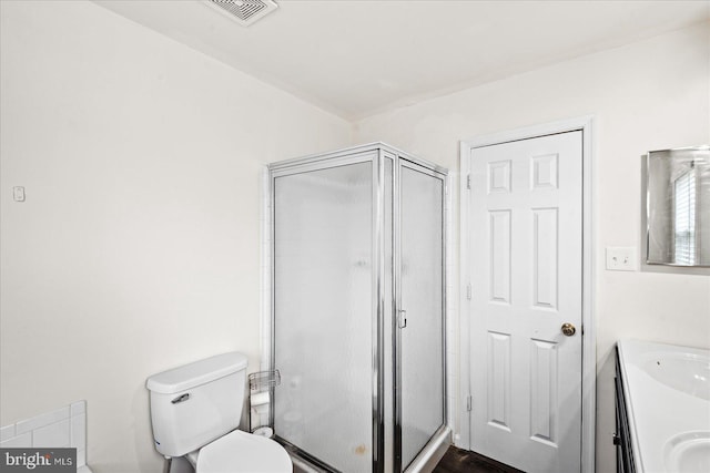 bathroom featuring vanity, toilet, and a shower with door