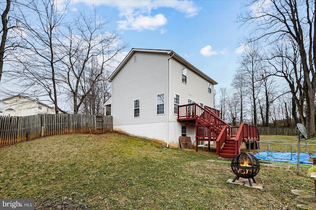 rear view of house featuring an outdoor fire pit, a lawn, and a wooden deck