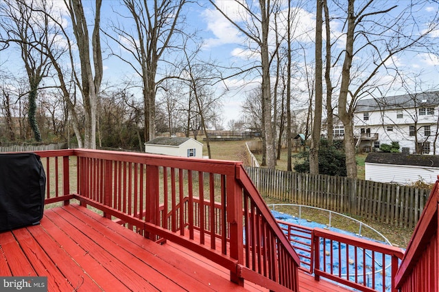 wooden deck featuring area for grilling and a storage unit