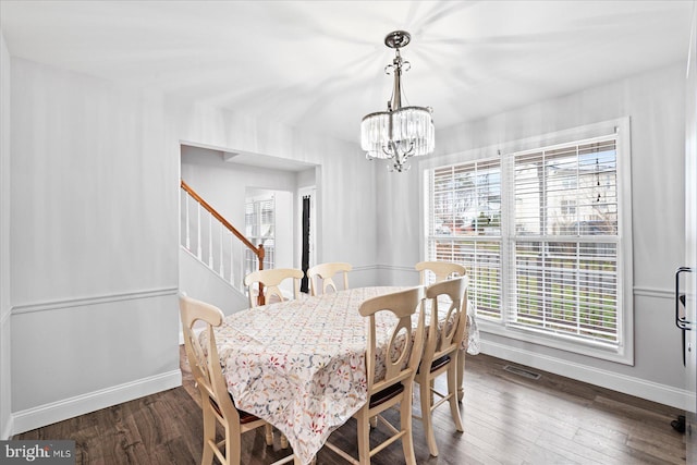 dining area with dark hardwood / wood-style floors, a healthy amount of sunlight, and an inviting chandelier