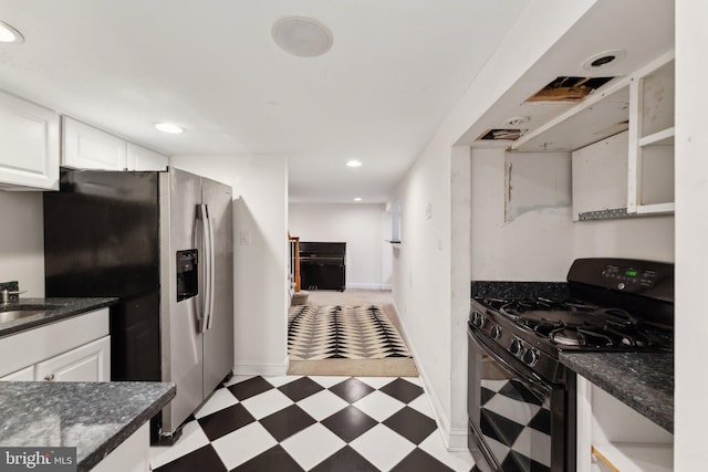 kitchen with dark stone counters, white cabinets, sink, stainless steel refrigerator with ice dispenser, and black gas range oven