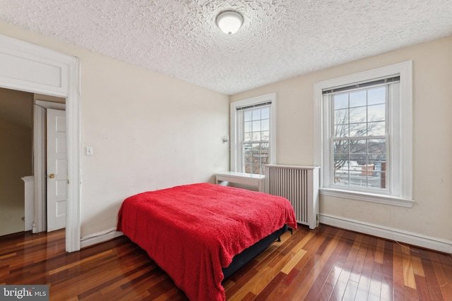 bedroom with radiator heating unit, a textured ceiling, and dark wood-type flooring