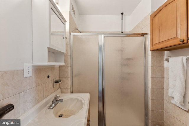 bathroom featuring backsplash, an enclosed shower, and sink