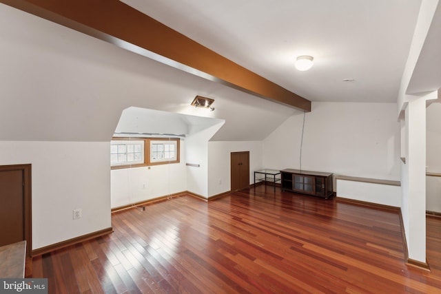 bonus room with lofted ceiling with beams and dark wood-type flooring