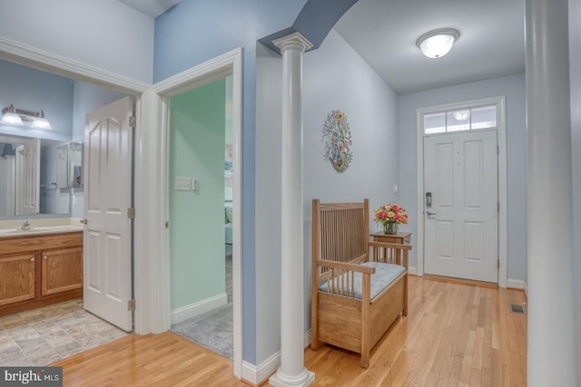 entrance foyer with light wood-type flooring, ornate columns, and sink