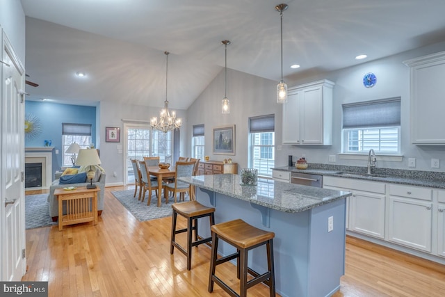 kitchen with white cabinetry, sink, a center island, a kitchen breakfast bar, and pendant lighting