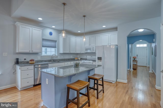 kitchen featuring a center island, white appliances, sink, and white cabinetry